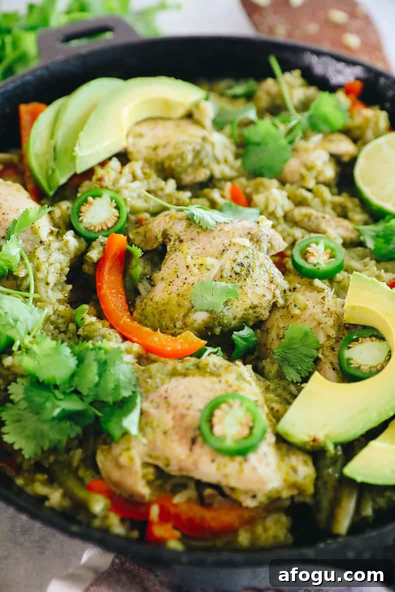 Cilantro Lime Chicken and Rice Recipe — One-Pot Dinner 7 close-up of a cooke chicken thigh with rice and veggies in a cast iron dish.