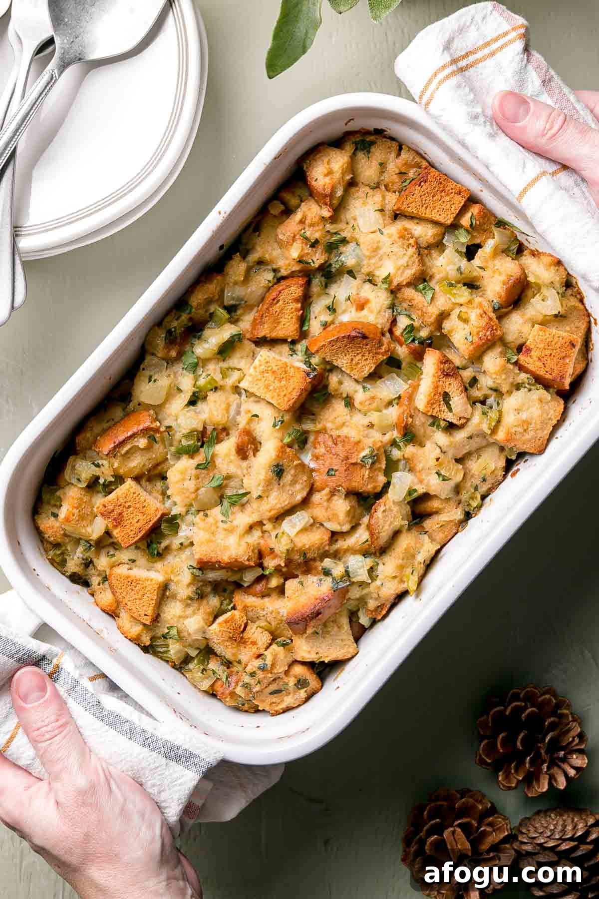 Hands with towels placing gluten-free stuffing on the table.