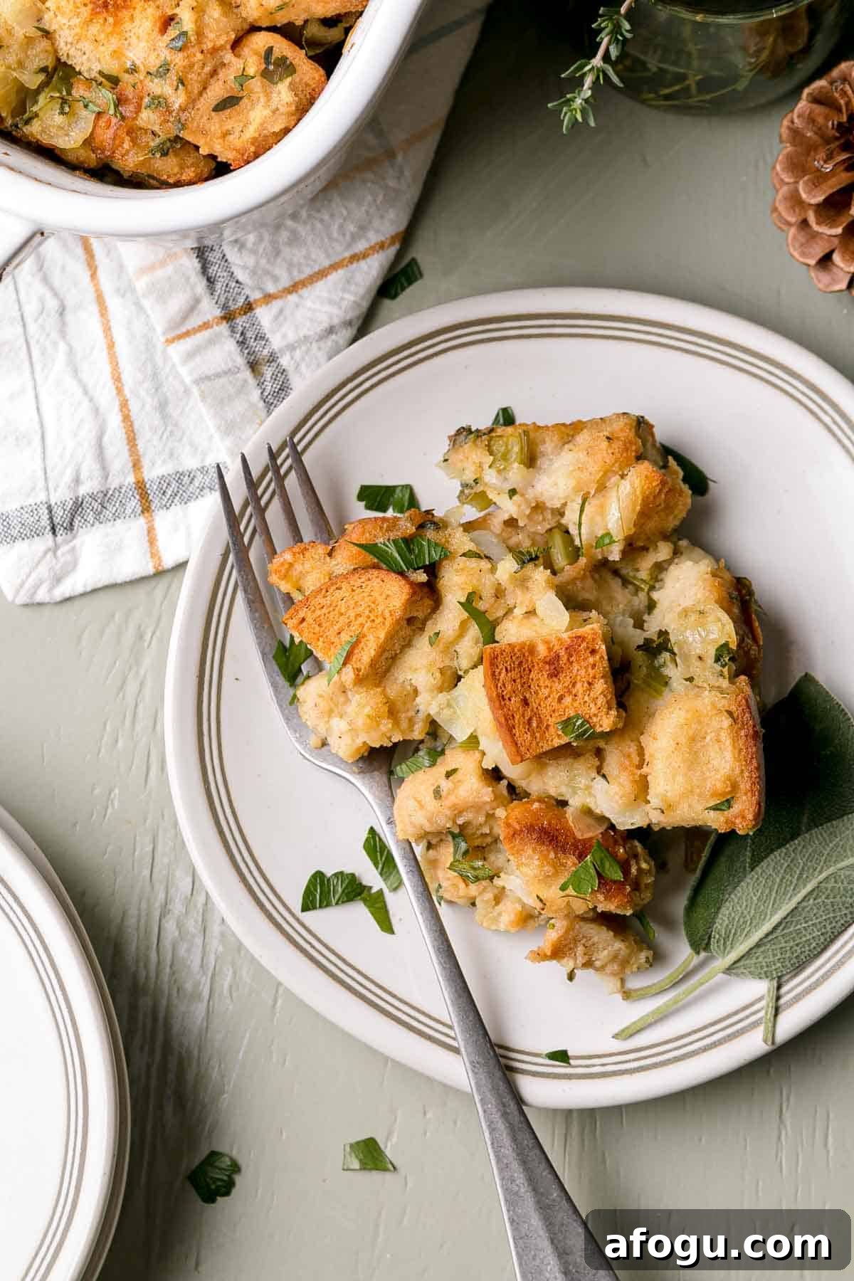 A serving of gluten-free stuffing on a small plate with a fork and sage leaves.