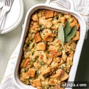 White Staub casserole dish with baked gluten free stuffing and sage leaves on top.