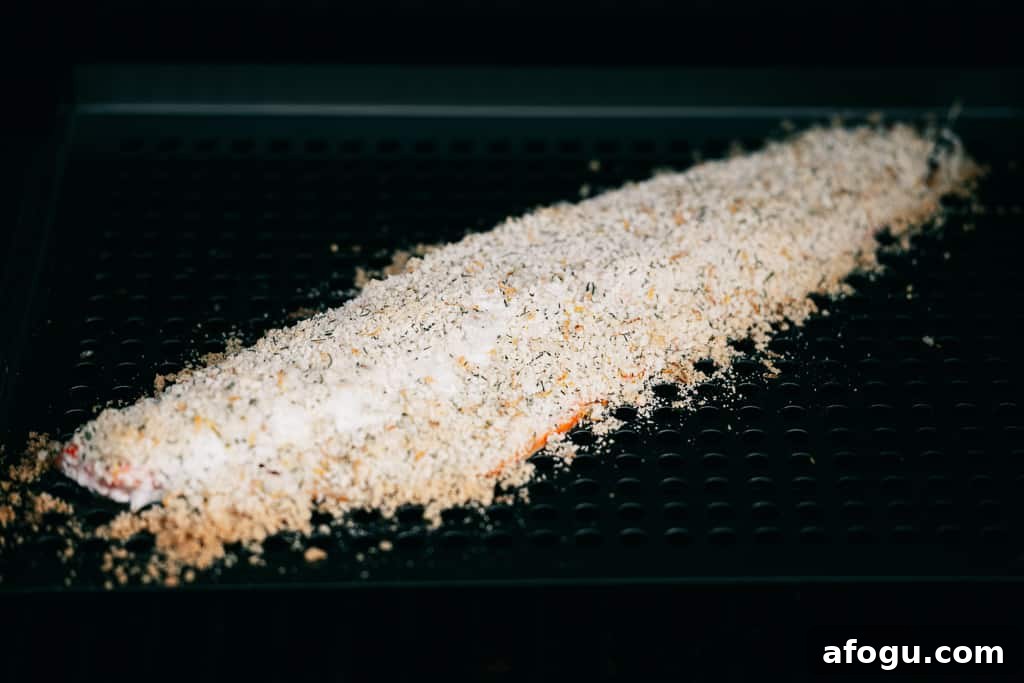 Parmesan sprinkled on the top of a salmon fillet on a grill.