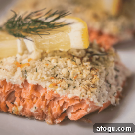 Parmesan crusted salmon garnished with lemon slices and dill.