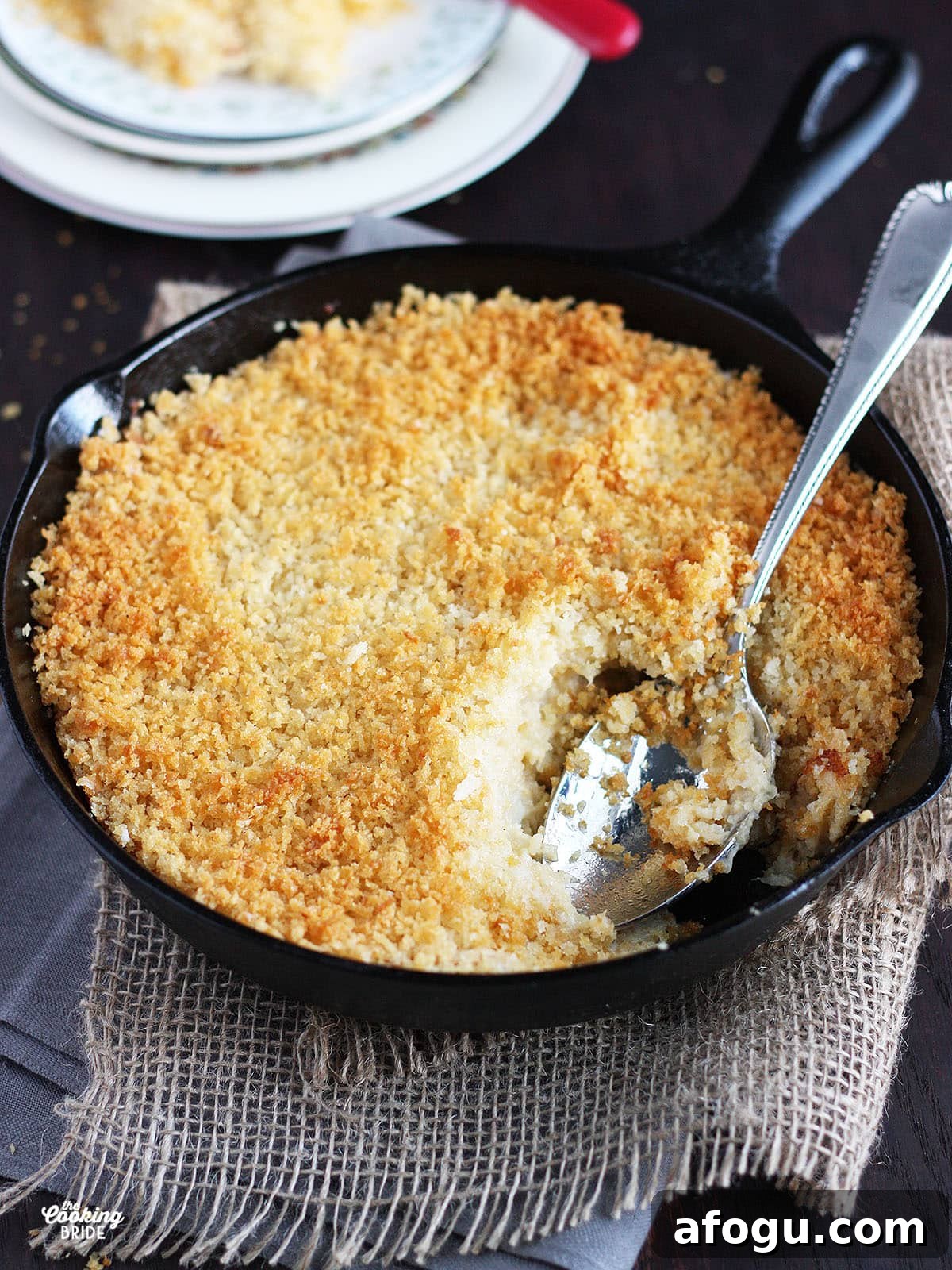 Creamy Cauliflower and Cheese Casserole Recipe 12 Mashed cauliflower and cheese casserole topped with Panko breadcrumbs in a cast iron skillet with a serving spoon.