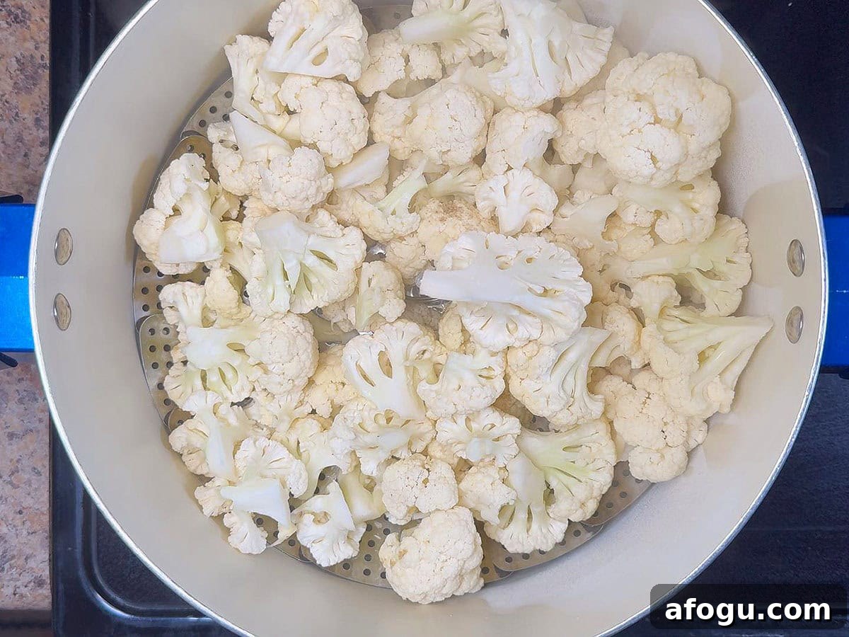 Creamy Cauliflower and Cheese Casserole Recipe 3 Cauliflower florets in a steam basket placed in a large stockpot.
