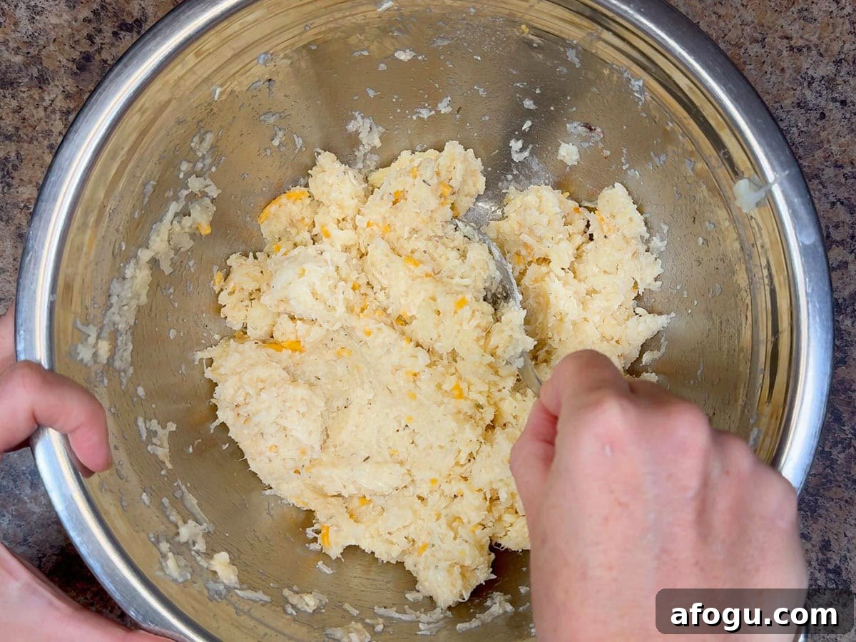 Creamy Cauliflower and Cheese Casserole Recipe 5 Mixing Parmesan cheese, Colby-Monterey Jack cheese, unsalted butter, garlic powder, Montreal steak seasoning, dried thyme leaves, and salt and pepper into the cooked and mashed cauliflower florets.