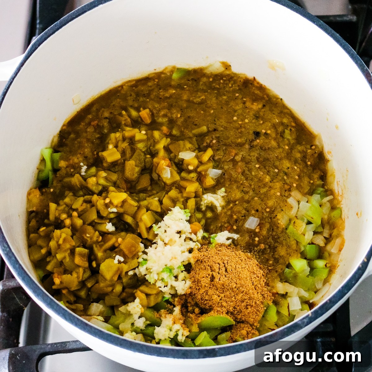 salsa, chiles, garlic, and cumin being stirred together.