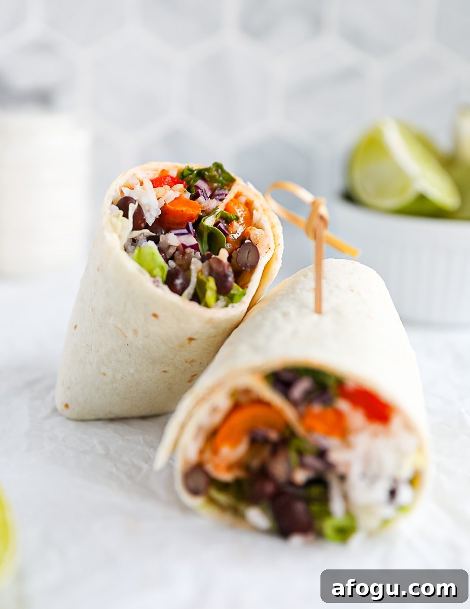 A sliced vegetarian burrito with one half leaning on the other half