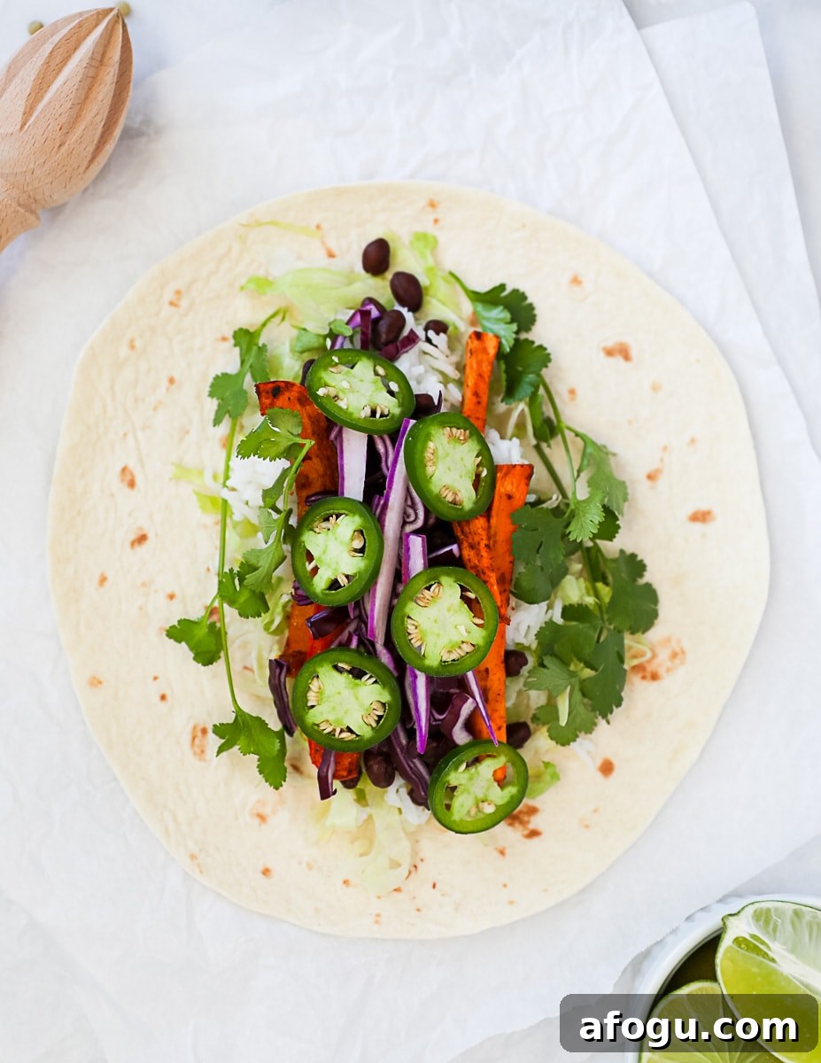 An unwrapped burrito filled with veggies and sliced peppers.