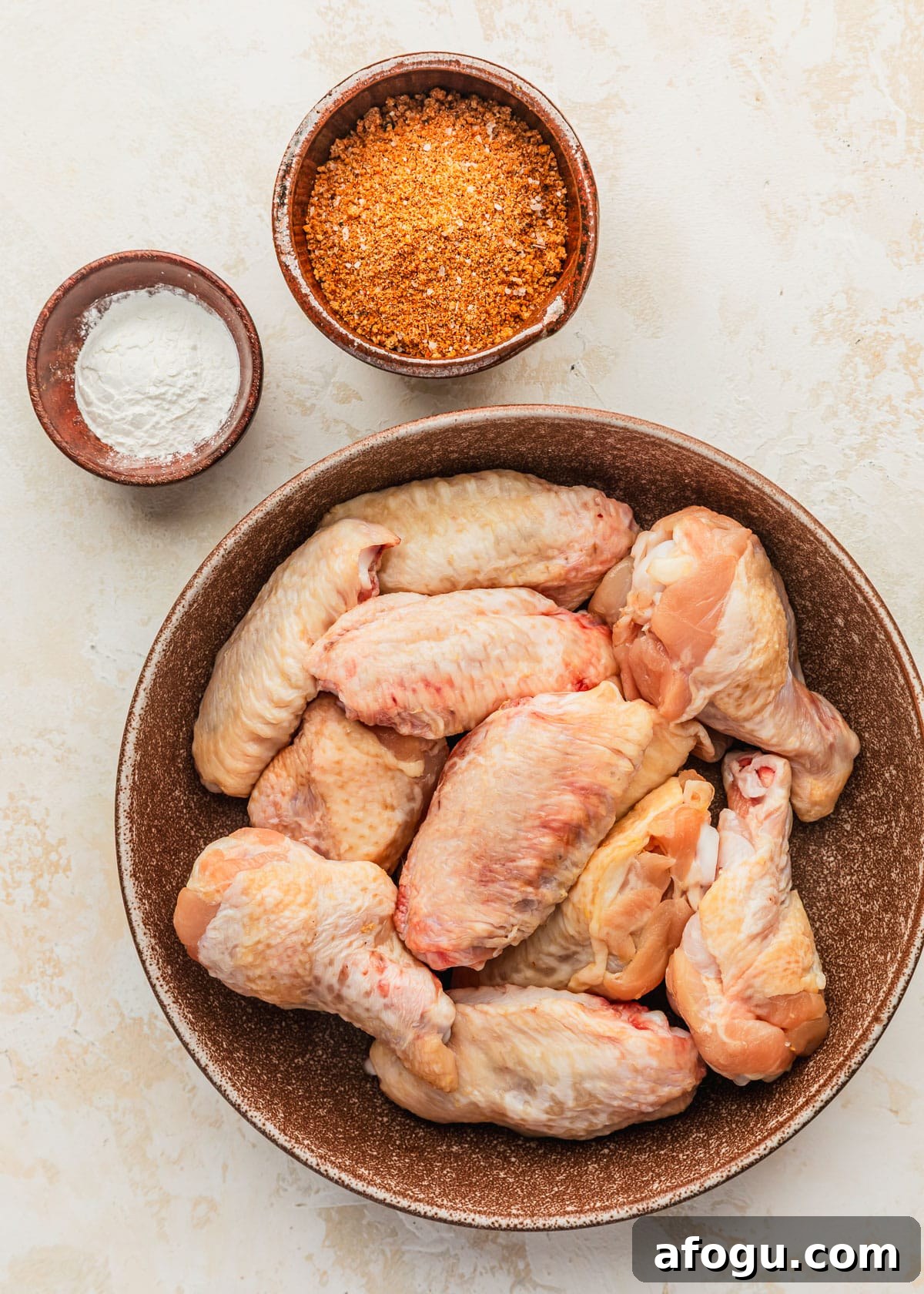 Crispy Dry-Rub Chicken Wings — Oven or Air Fryer Recipes 3 Brown bowls of chicken, spices, and baking powder on a beige counter.