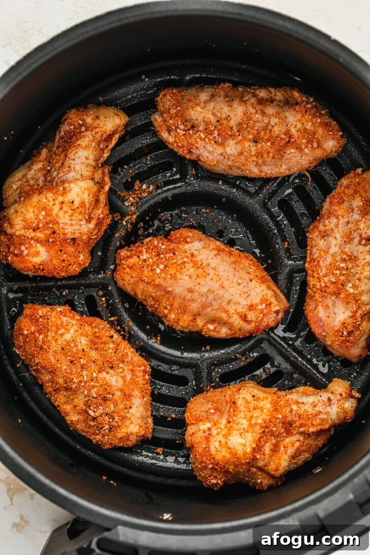 Crispy Dry-Rub Chicken Wings — Oven or Air Fryer Recipes 6 Raw dry rub chicken wings in an air fryer basket.