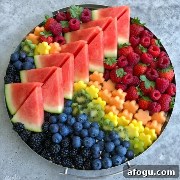 Elegant Fruit Platter Ideas for Special Occasions 6 A round tray filled with a vibrant fruit medley—neatly arranged slices of watermelon, piles of raspberries, strawberries, blackberries, blueberries, kiwi, and flower-shaped pieces of cantaloupe and honeydew melon.