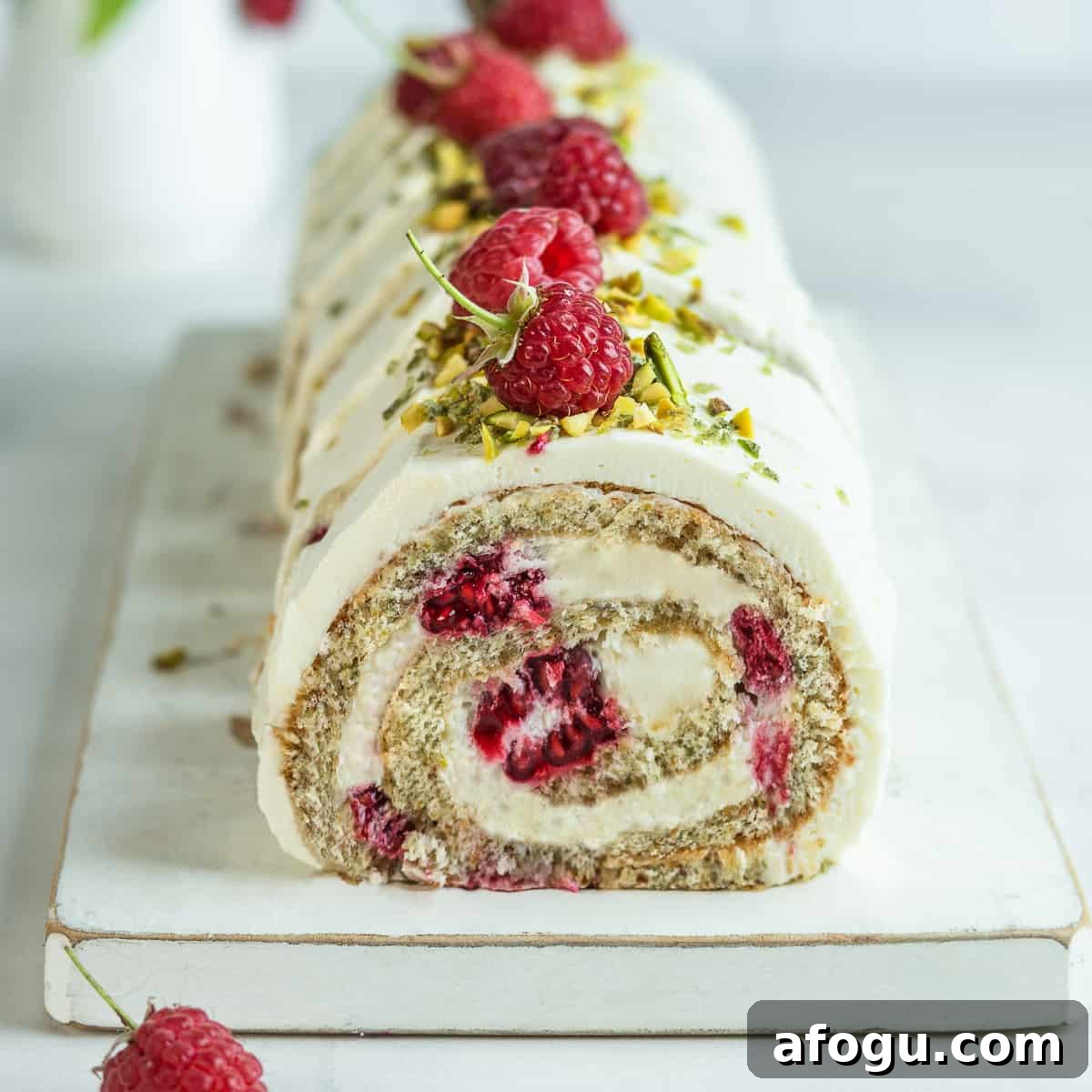 Sliced pistachio Swiss roll on a white cake board 
