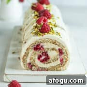 Sliced pistachio Swiss roll on a white cake board.