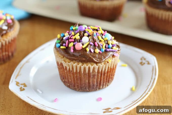 Vanilla cupcake with frosting on a white plate.