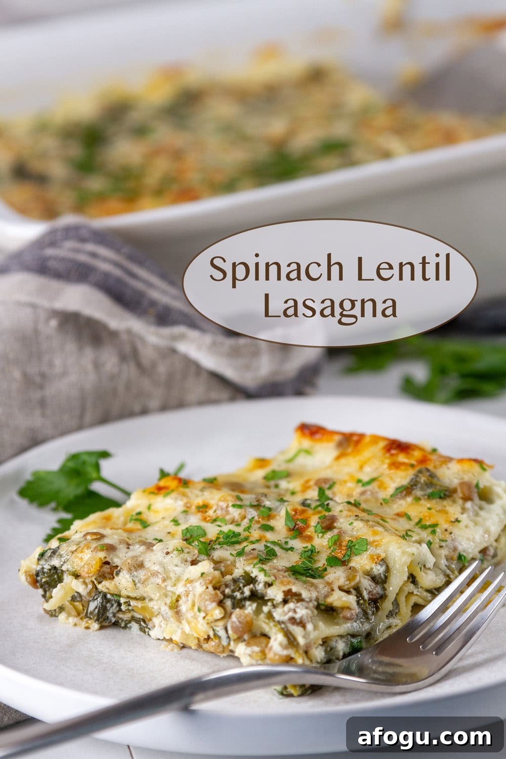 a slice of spinach lentil lasagna on a white plate in front of the casserole dish of lasagna. 