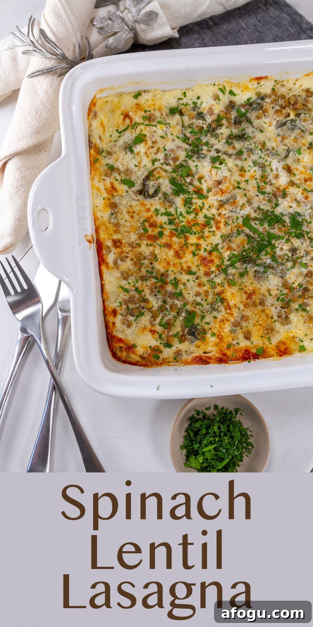 Looking down on the casserole dish of lasagna with some forks and fresh herbs around the dish.