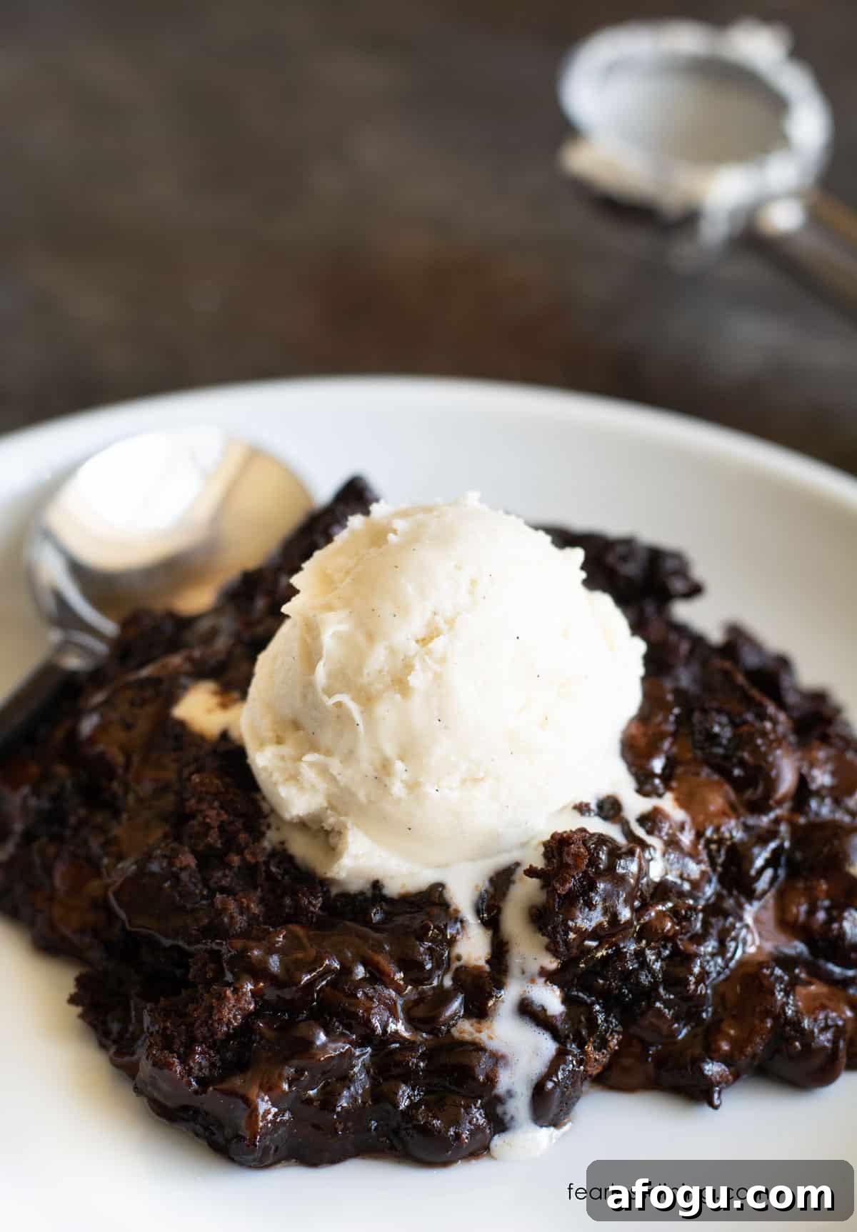 Gluten-Free Slow Cooker Chocolate Lava Cake Recipe 2 A plate with chocolate lava cake. It is topped with a scoop of vanilla ice cream.