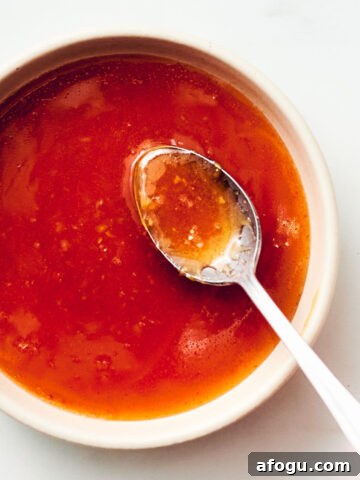 Easy honey sriracha sauce in a bowl with a spoon.