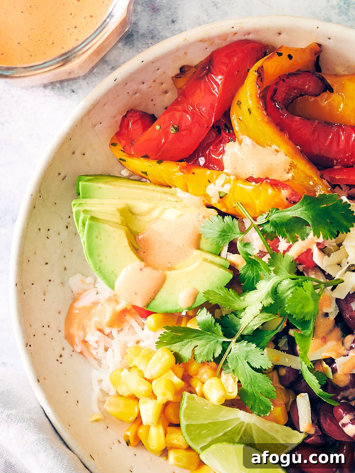 Rice bowl with air fryer peppers, avocado, beans, and red pepper crema. 