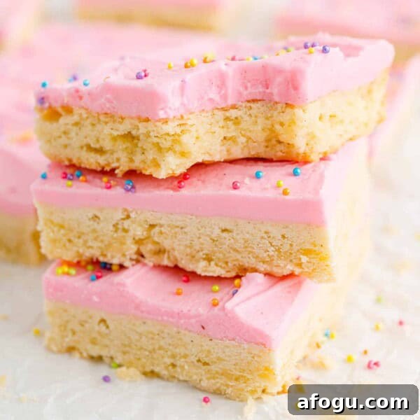Sugar cookie bars with pink frosting and sprinkles, stacked three high.
