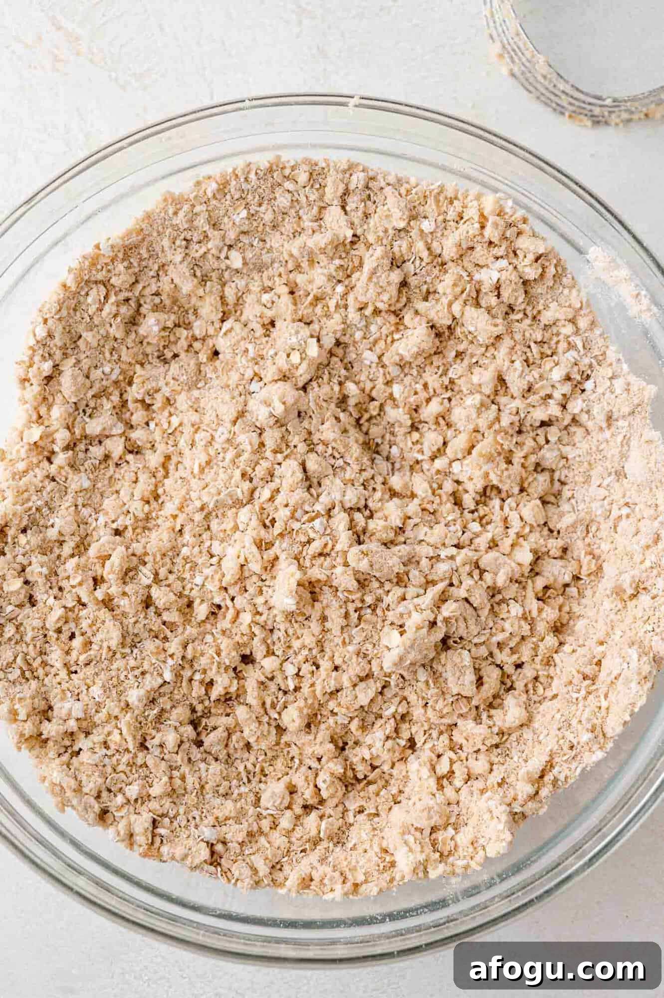 Crust mixture in clear bowl, showing texture of coarse crumbs.