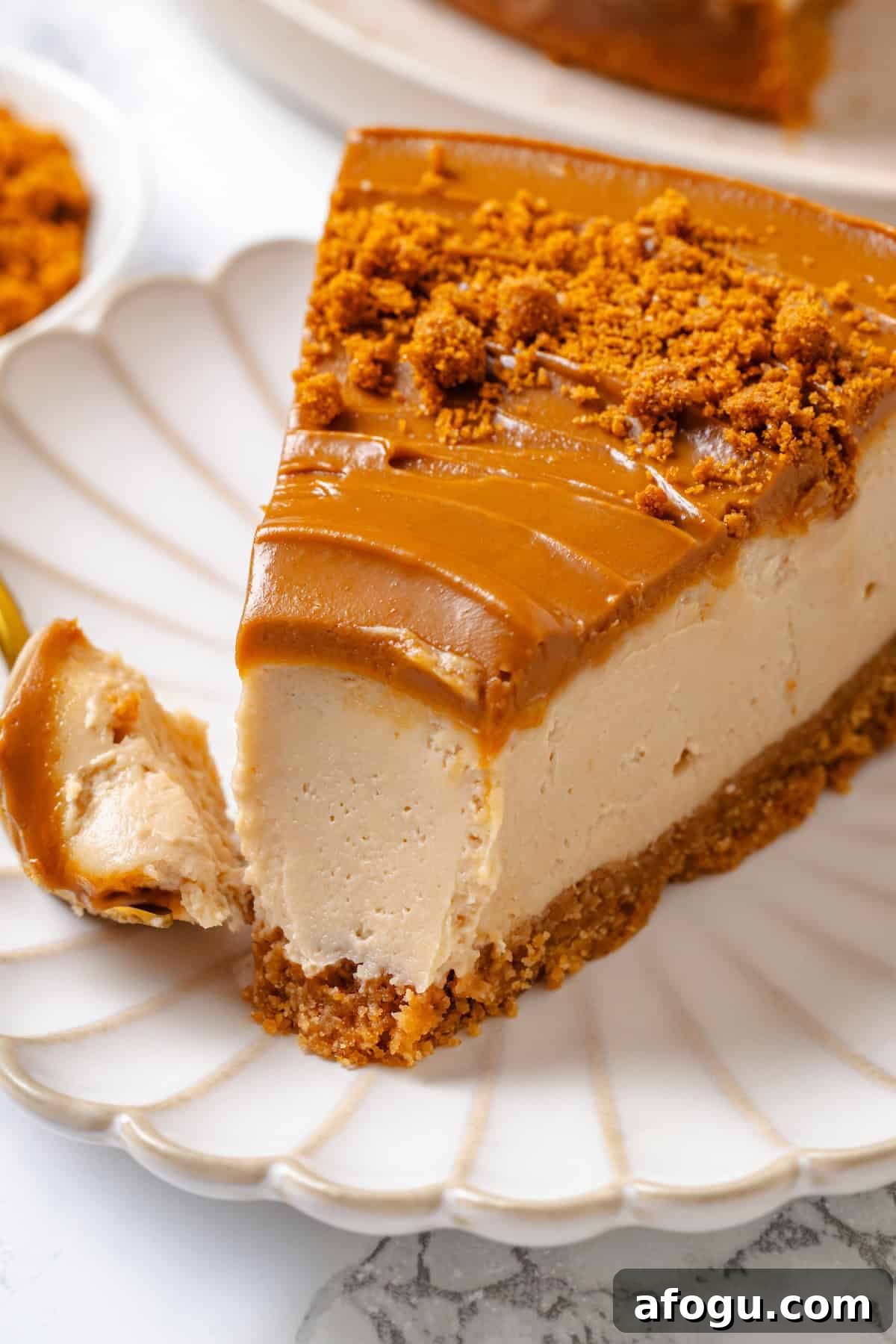 Slice of Biscoff cheesecake on plate with tip on fork.