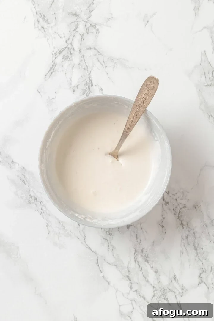 Coconut cream mixed with cornstarch in bowl with spoon.