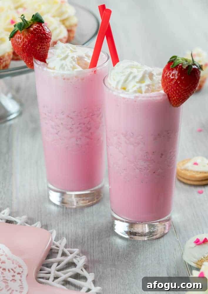 Strawberry ice cream milkshake with whipped cream and fresh strawberry garnish.