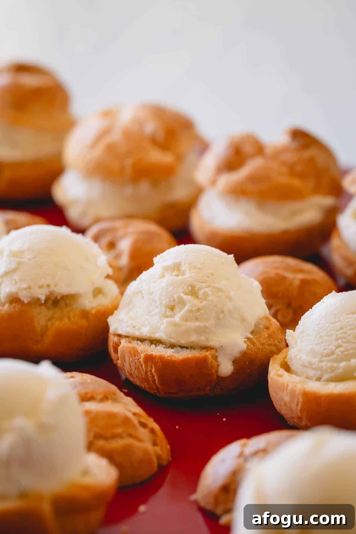 Profiteroles being topped with ice cream.