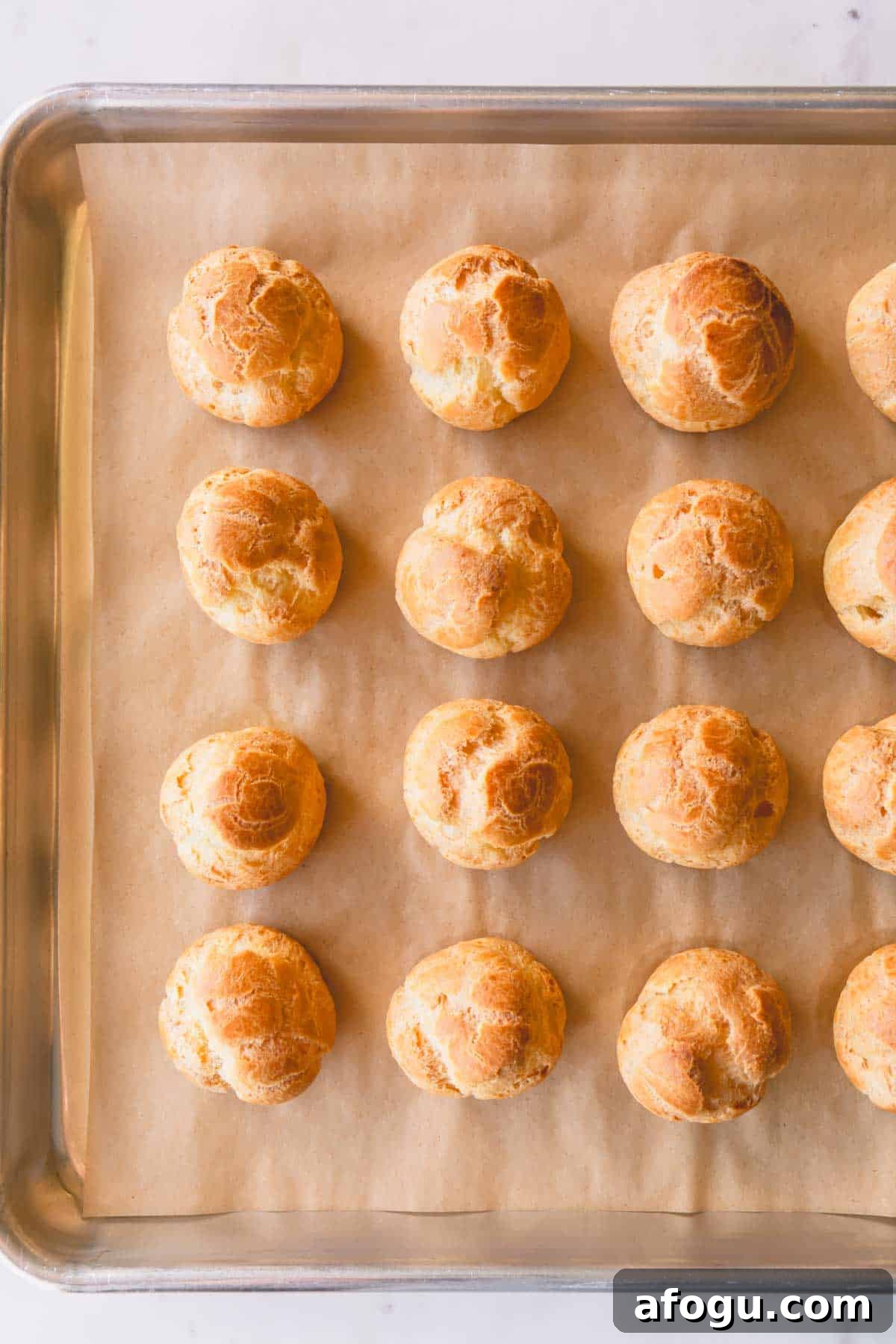 Baked profiteroles shells on a baking sheet.