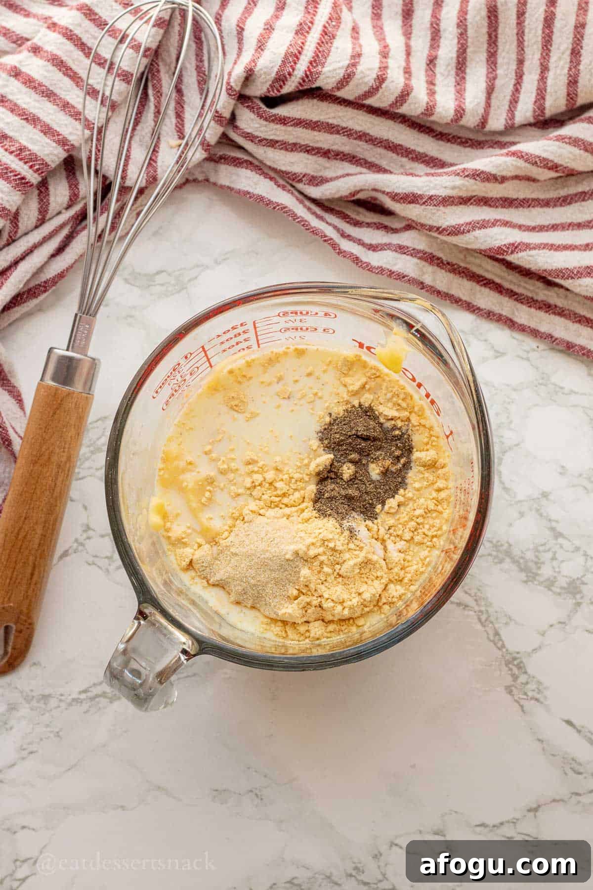 Milk, seasonings, and gravy mix in glass measuring cup.