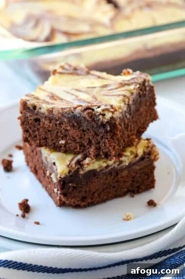 Two marble brownies stacked on a plate.