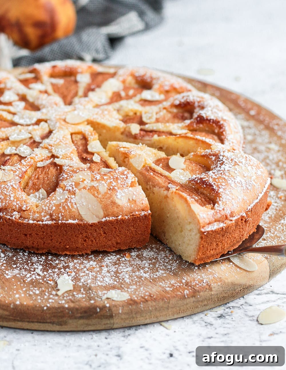 A slice of the pear cake cut off on a wooden board.