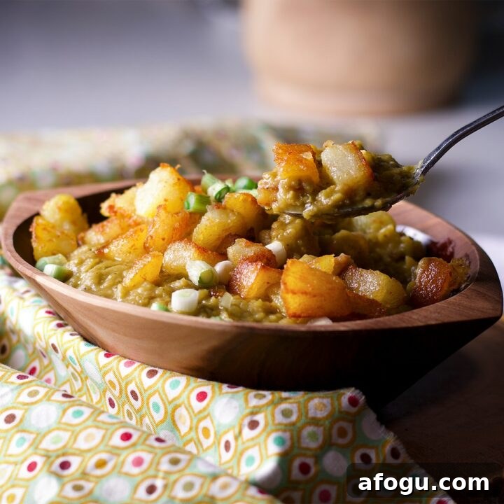Someone lifting a spoonful of split pea soup from a wood bowl.