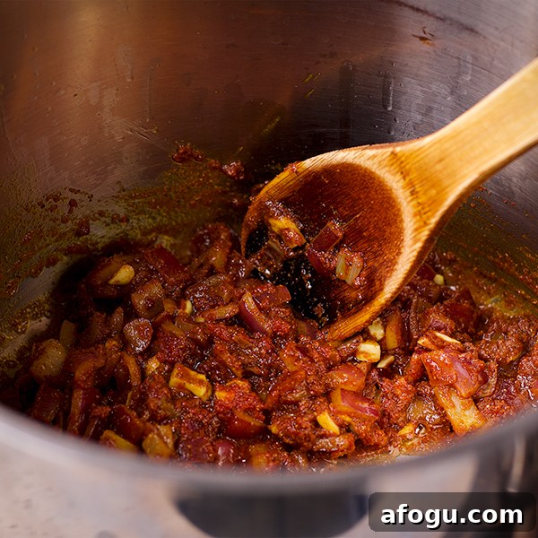 Stirring a pot of vegetables and spices to make Curried Roasted Cauliflower soup.