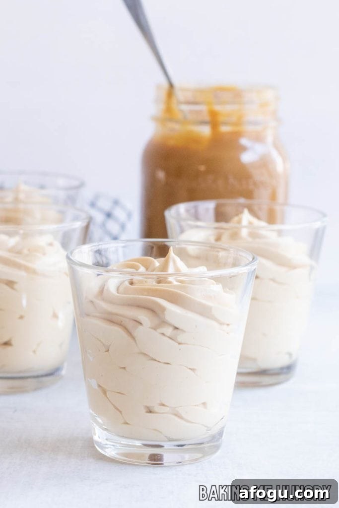 caramel mousse in small glasses in front of a jar of caramel sauce