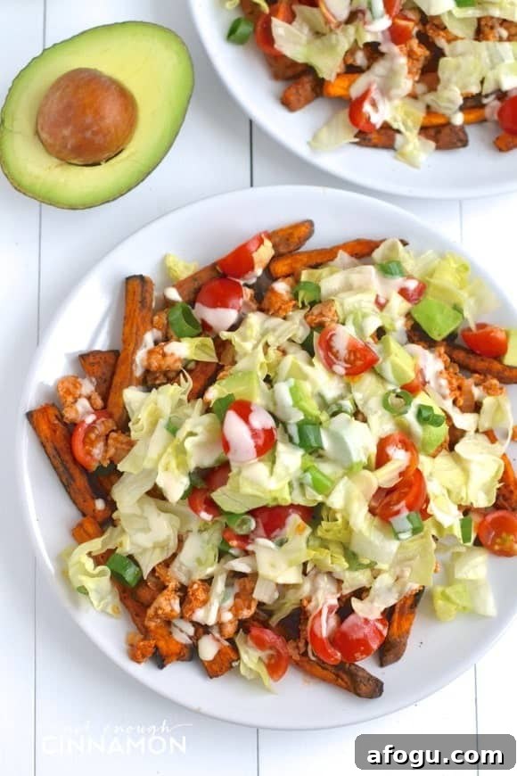 overhead shot of Clean Eating Turkey Taco Loaded Baked Sweet Potato Fries in a white plate with half an avocado on the side 