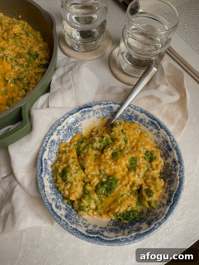 Gluten Free and Nut FreeCheesy Vegan Rice with Broccoli in a blue and white glass dish with spoon and bowl of the vegan cheesy broccoli rice recipe. 