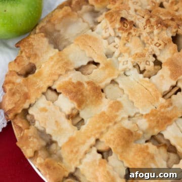 Lattice Apple Pie sitting on a red table, granny smith apple on table.