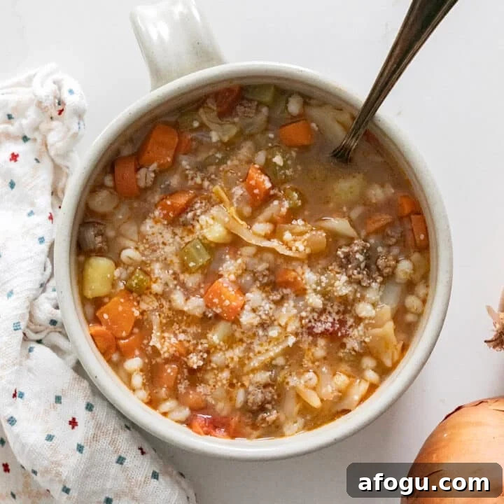 An overhead image of a bowl of cabbage soup with a spoon in it.