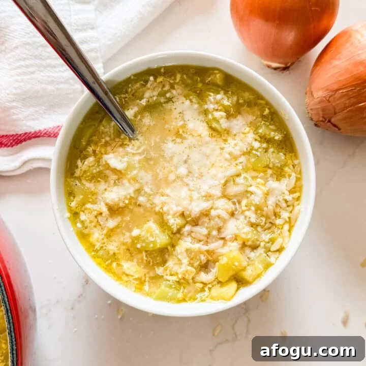 An overhead image of a bowl of zucchini soup with onions and a tea towel next to it.