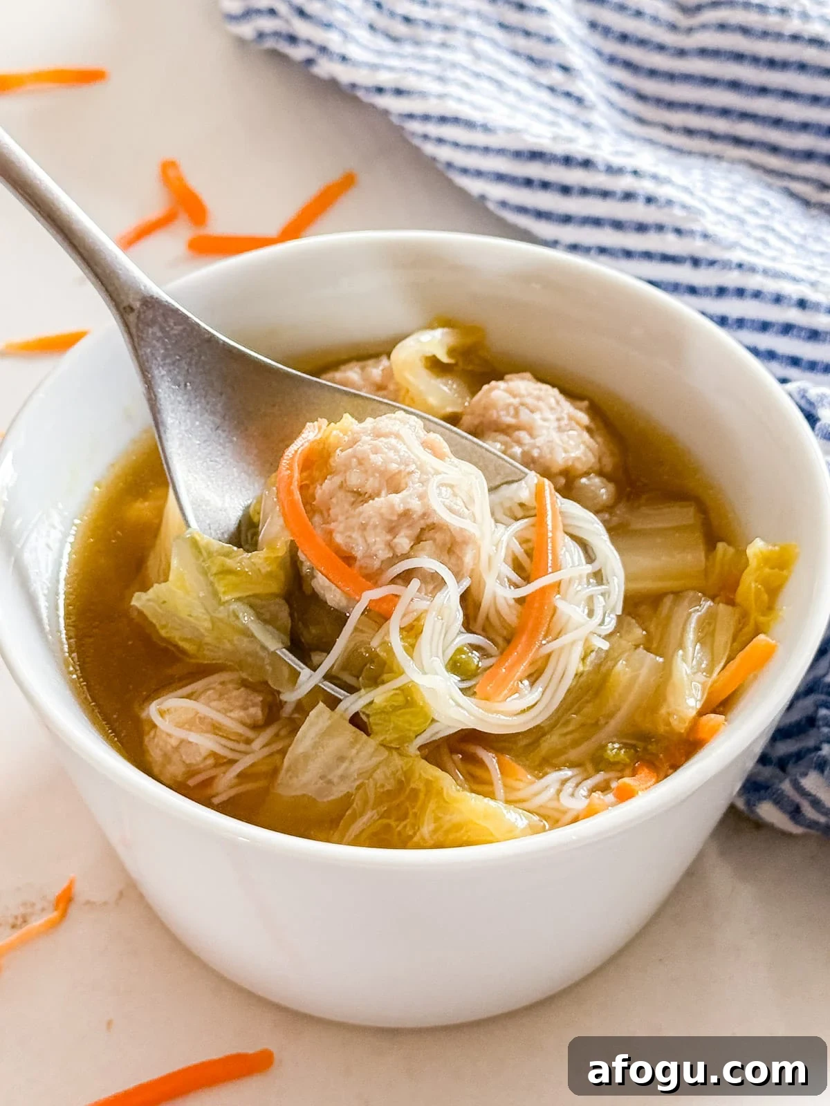 Asian Cabbage and Pork Meatball Soup Recipe 10 A close up of a spoon of soup and meatballs being lifted from the bowl.