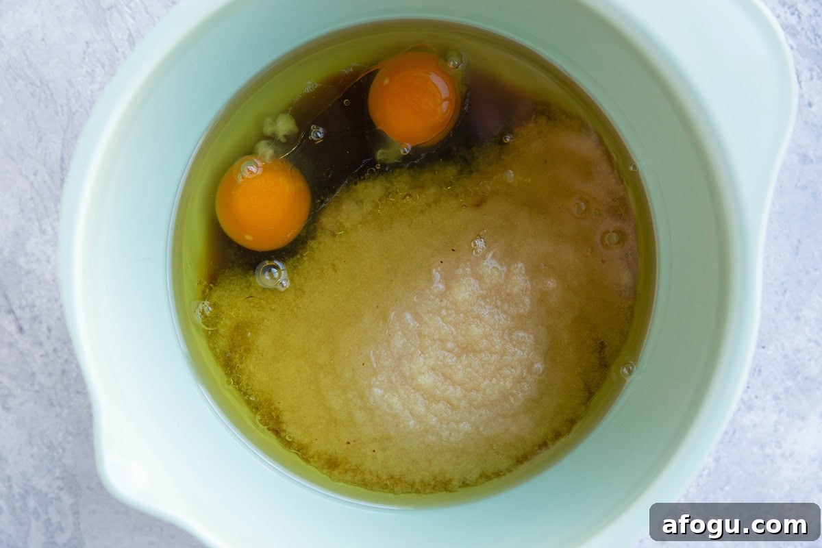 Mixing bowl with applesauce, maple syrup, eggs, and avocado oil.
