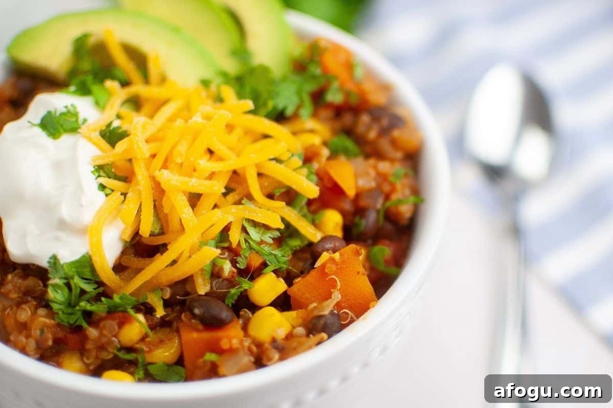 Sweet Potato Chili with Quinoa topped with avocado, cream, grated cheese, and cilantro.