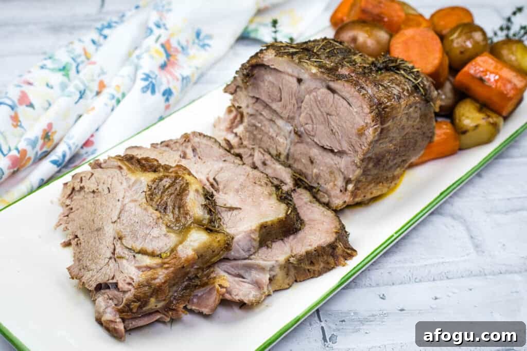 Slow Cooker Herb-Crusted Pork Roast with slices and roasted vegetables on a plate.