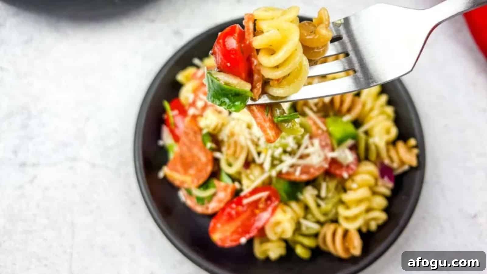 A fork with pizza pasta salad in a bowl.