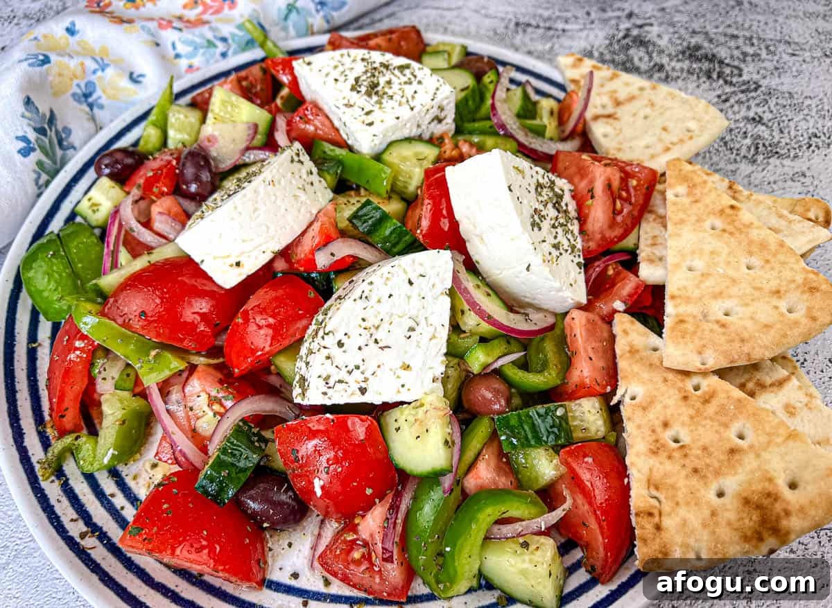 Horiatiki Salad with feta cheese on top served on a plate.