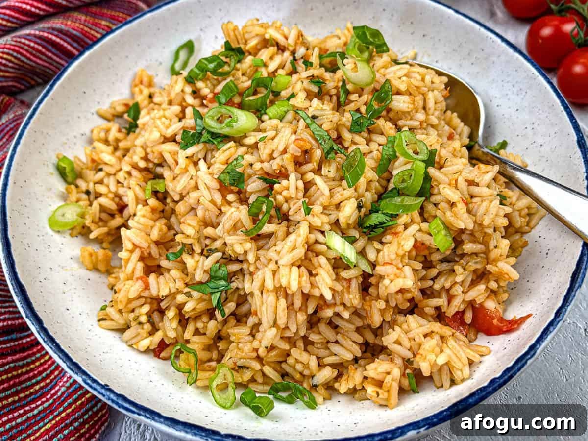 A plate of Mexican rice garnished with chopped green onions and herbs served with a spoon.