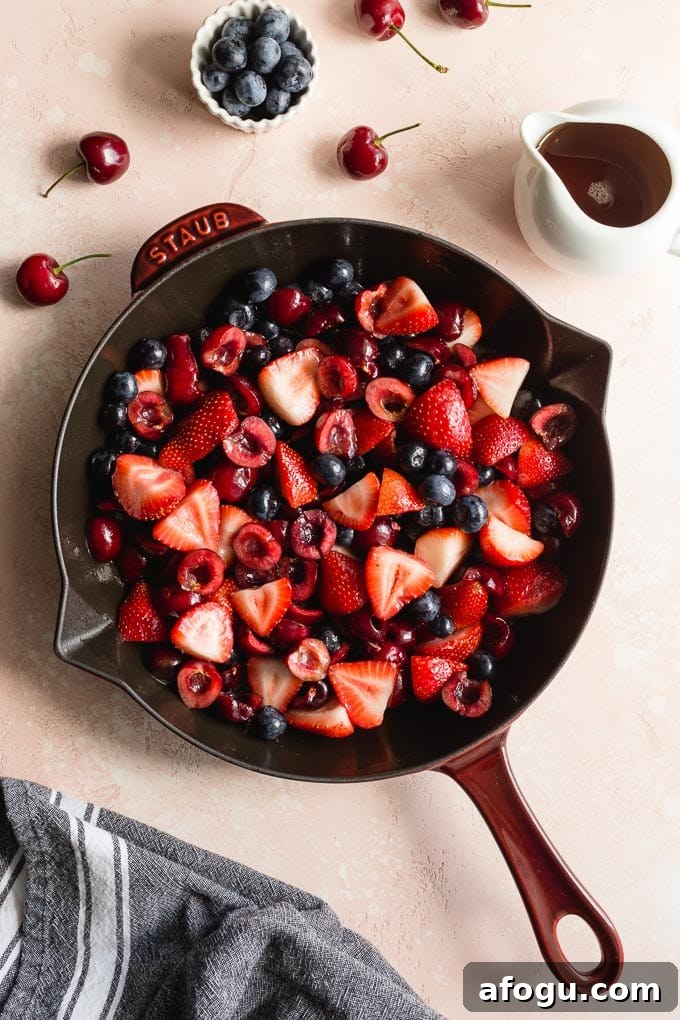 Cherries, strawberries and blueberries in a cast iron skillet.