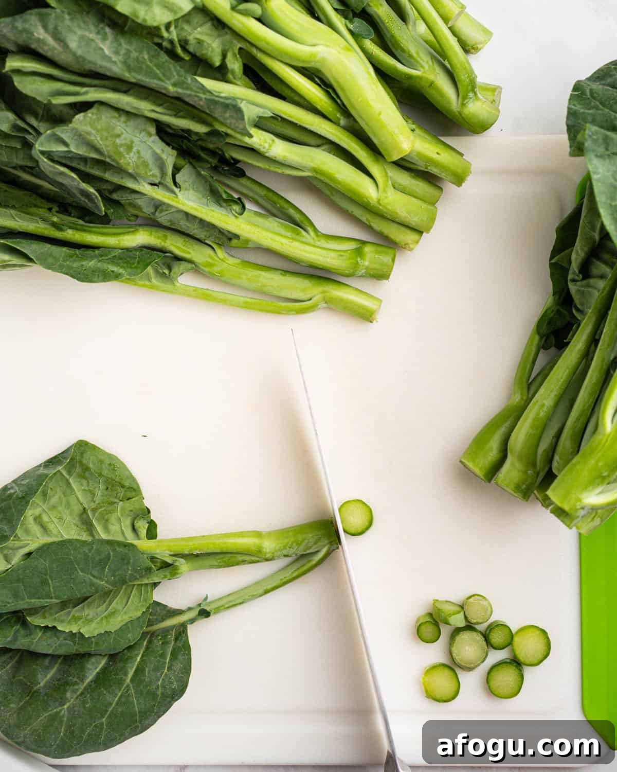 Cutting stem of Chinese broccoli on cutting board.